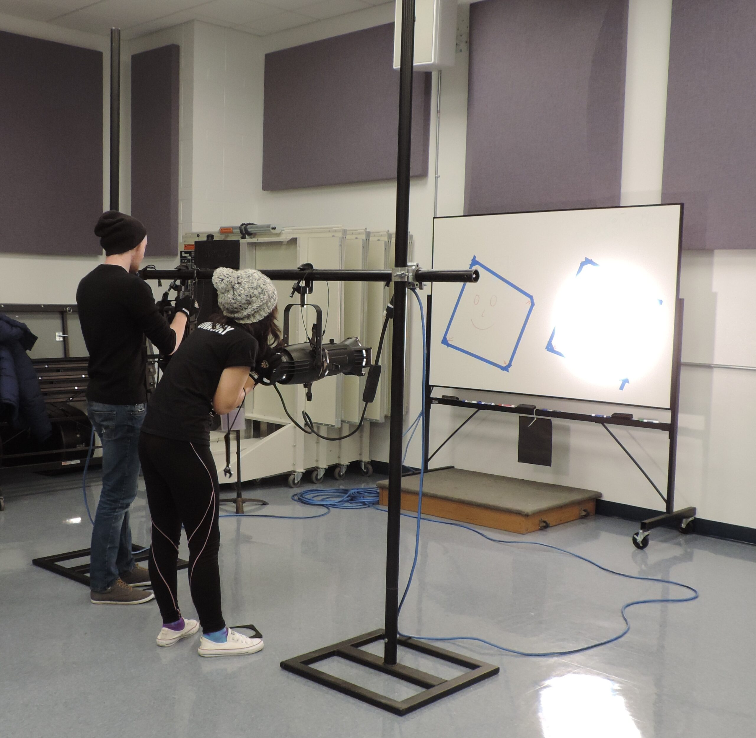 Photograph showing students hanging and focusing a light.